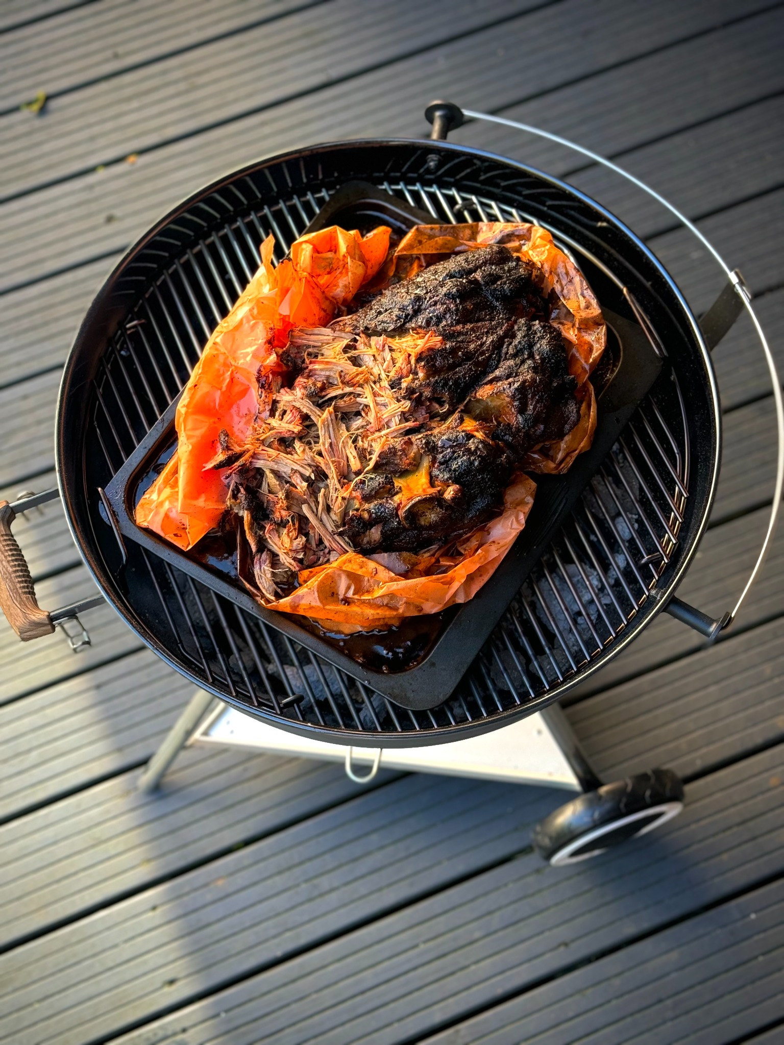 Smoked pork being pulled apart on a kettle barbecue